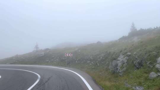 在大雾中行驶在山区道路上的电影视图。