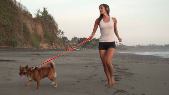 女子和狗在海滩上跑步视频素材模板下载