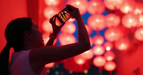 女人用红灯笼在手机上拍照