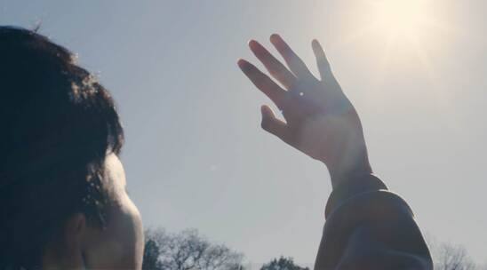 男孩伸手遮挡阳光，阳光穿过指缝视频素材模板下载