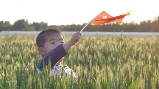 中国小朋友在麦田地中挥舞着旗帜玩耍泡吹泡