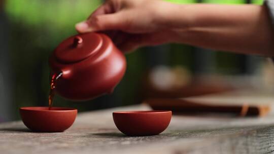 茶艺师拿起紫砂壶往茶杯里倒红茶