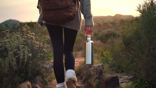 一个女人在手拎着水杯走路