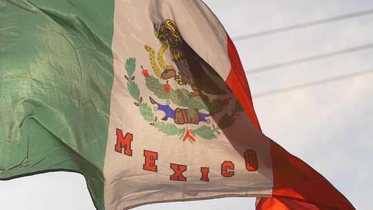 墨西哥国旗在阳光下飘扬。慢动作它在天空中视频素材模板下载
