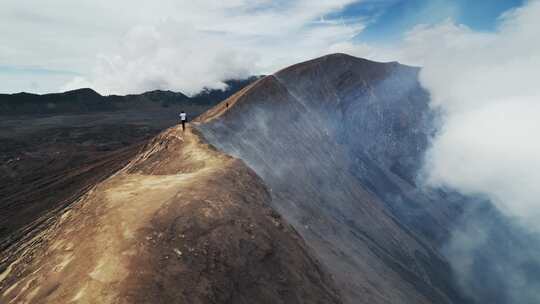 沿着火山上方的山脊行走的人