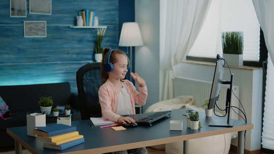 孩子在电脑上的视频通话网络摄像头上挥手上学