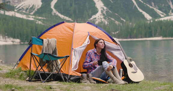 露营地上的一个美丽的女人在帐篷前欣赏大自