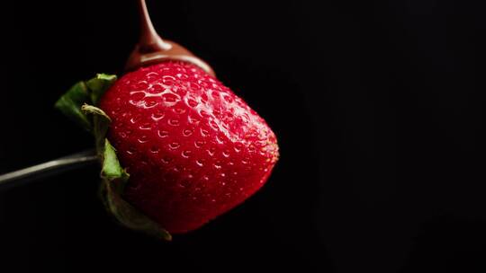 巧克力果酱倒在草莓上的画面特写