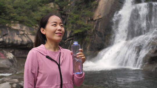 亚洲中国人女性在瀑布下喝水饮用水