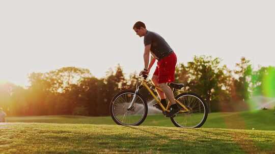 日落时骑自行车的人在草坪上骑行视频素材模板下载