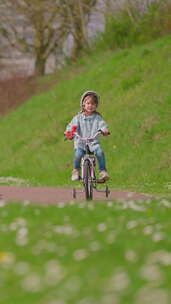 垂直视频戴着白头盔的可爱小女孩骑着自行车