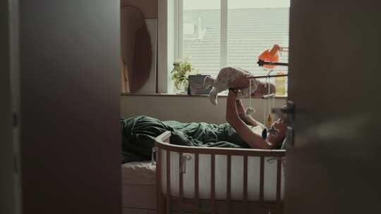 父亲玩与新生的儿子在卧室在早上