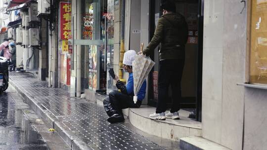上海南京路雨天行人撑伞路边坐着