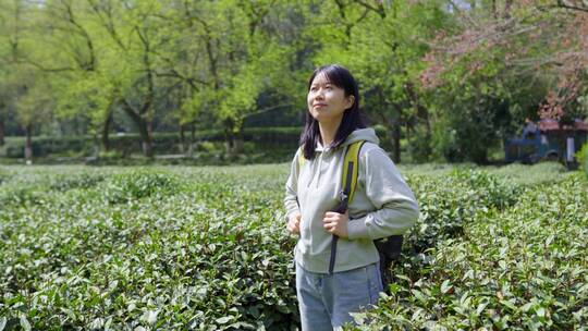 春天年轻女孩郊游茶园背包走路穿过清新茶树