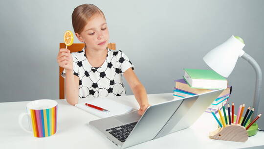 女生拿着棒棒糖在玩笔记本电脑