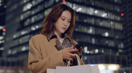 城市街头玩手机的女青年视频素材模板下载