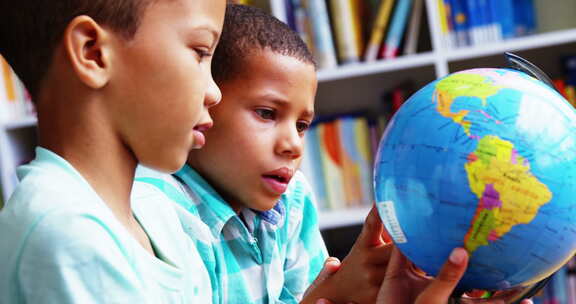 小学生在学校图书馆看地球仪