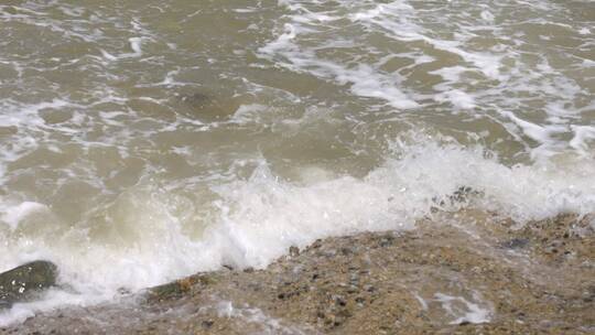 实拍浪花拍打在海边的礁石上