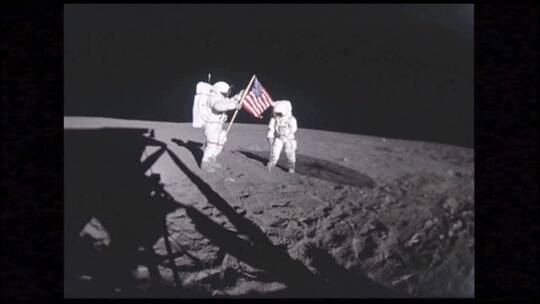 宇航员拿着国旗站在月球表面