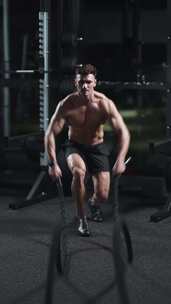 运动男子在健身房电影灯光下用战绳进行耐力