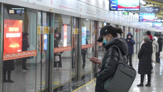 一名女子玩着手机等地铁
