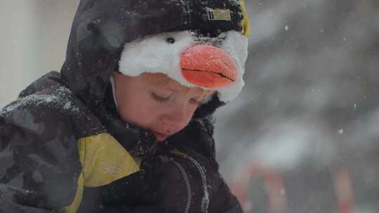 小男孩站在雪地里往下看