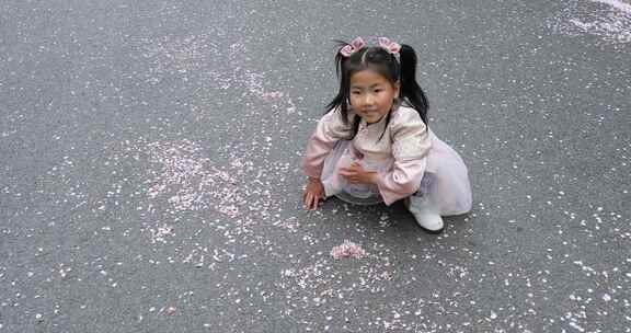 小女孩将落花花瓣堆成一个心形 开心笑容