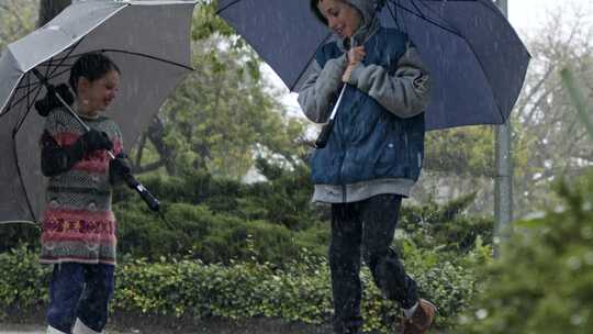 女孩和男孩拿着雨伞在雨中跳上跳下