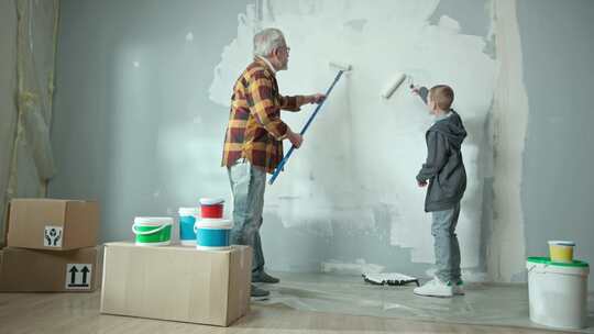 从祖父和孙子的背面看用油漆滚筒用白色油漆粉刷墙壁