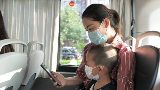 亚洲中国人女性和小朋友坐公交车看手机