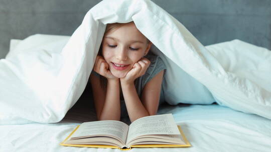 趴在床上盖着被子读书的女孩视频素材模板下载
