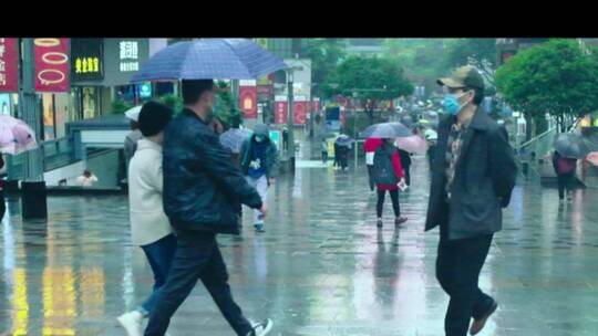下雨天行人打雨伞穿过步行街