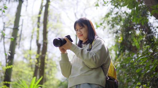 春天年轻女孩郊游公园手拿相机拍摄美丽景色