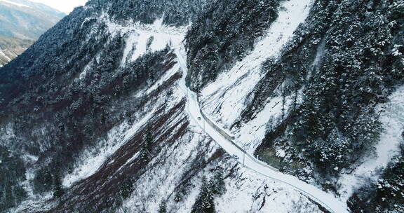 航拍自驾游汽车行驶在白雪皑皑的盘山路上