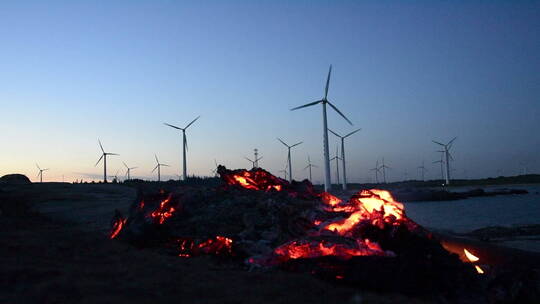 傍晚海边风力发电和火堆