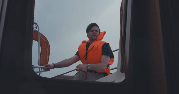 男子穿着救生衣坐在船上