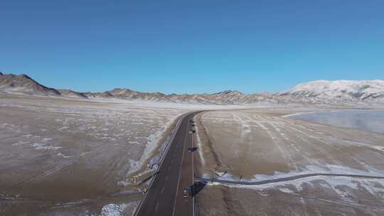 航拍冬季新疆赛里木湖环湖车辆行驶雪山公路