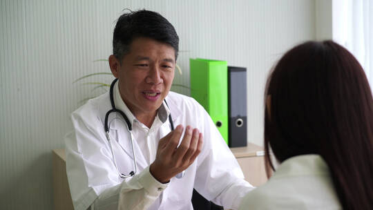 亚洲医生和病人正在讨论一些事情过肩镜头