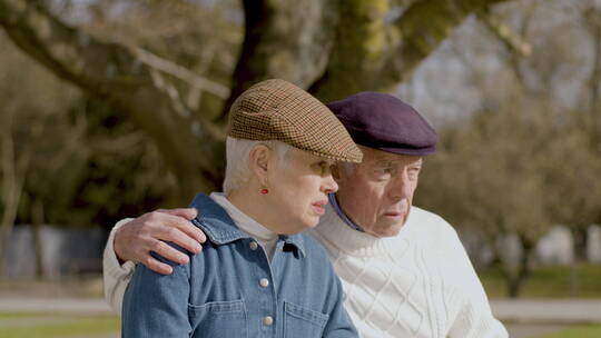 老年夫妇坐在公园长凳上聊天接吻