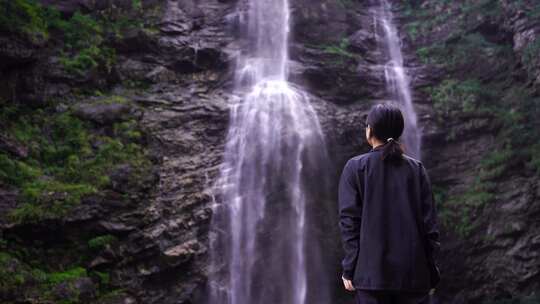 女性游客背影面向山水感受亲近自然山峰瀑布