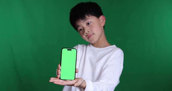 可爱的中国小男孩展示绿屏智能手机