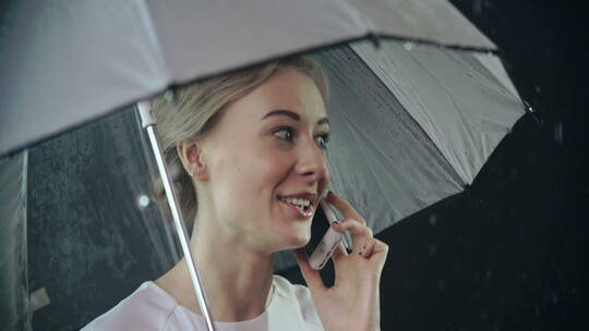 女人在雨天打着伞打电话