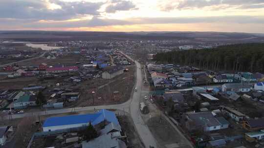 村庄春天傍晚的鸟瞰图。汽车沿着公路行驶