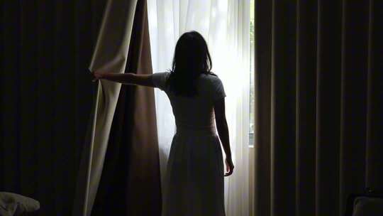 女人拉开窗帘看见第一缕阳光