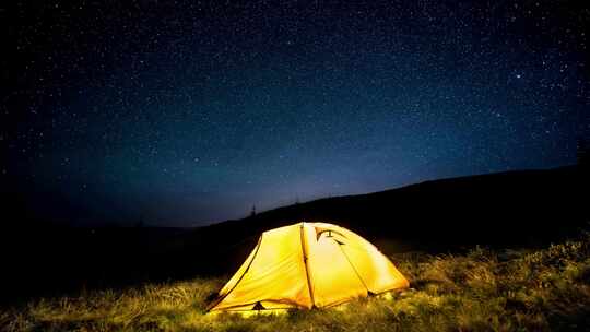 星空下夜山森林中发光的露营帐篷。时间流逝