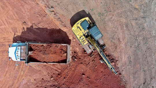 一台挖掘机正在建筑工地将泥土装入自卸卡车视频素材模板下载
