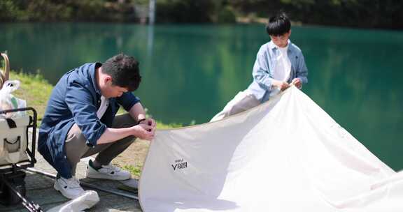 一对父子正在湖边扎帐篷 露营 踏青