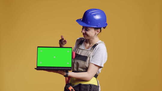 女建筑工人拿着带绿屏的电脑