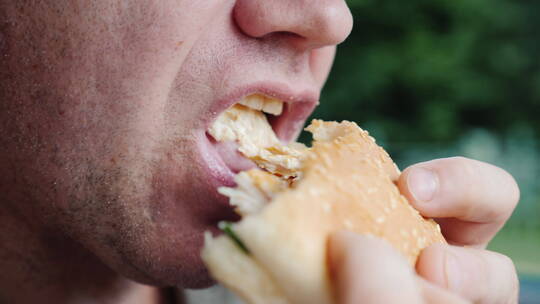 一个饥饿的男人急切地吃汉堡包
