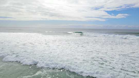 冲浪者骑着巨大的海浪在蓝色天空的云景在伯